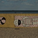 Graffiti na Bulwarze Nadmorskim w Gdyni. Facet z brodą się opala, obok piłka leży